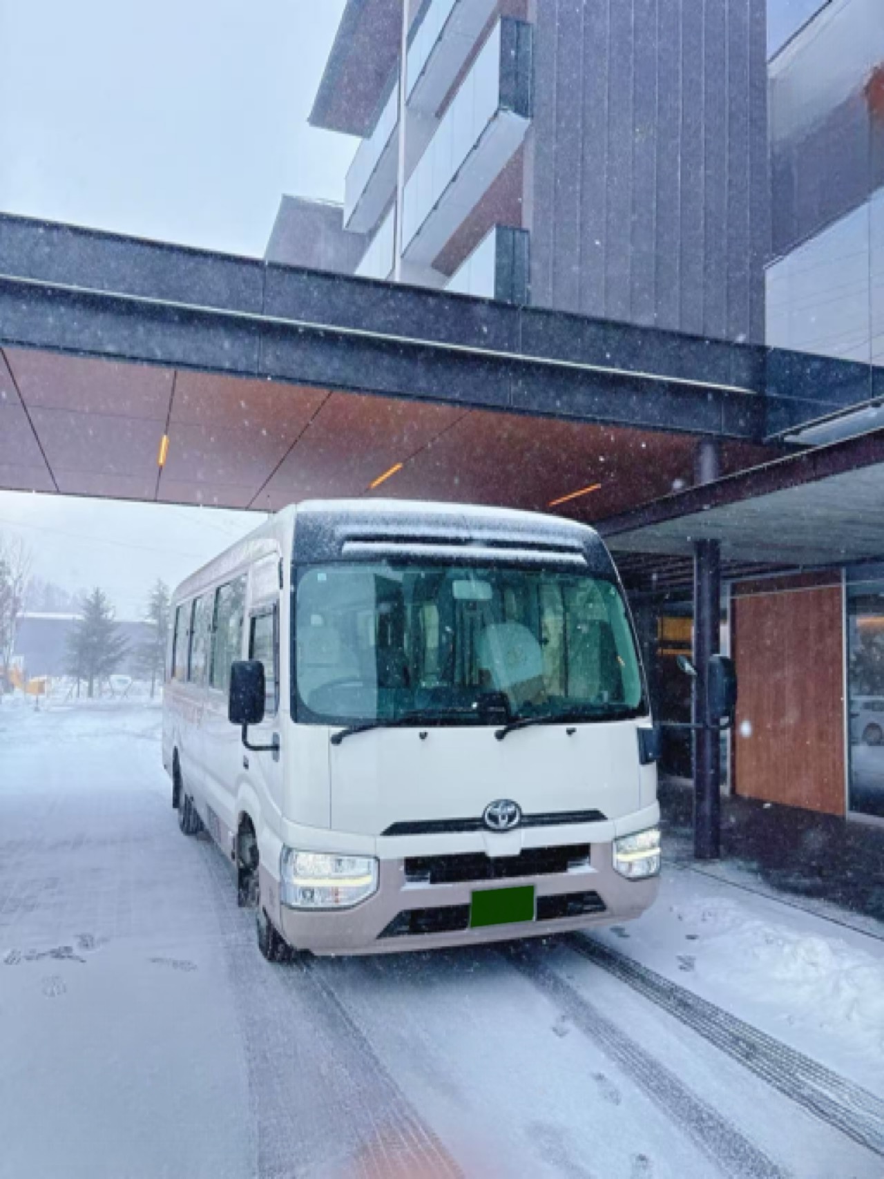 18-seat private microbus outside a Hakuba hotel during snowfall